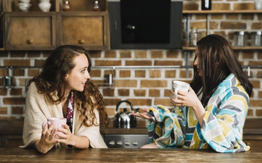 two-female-friends-drinking-cup Deux femmes buvant du café en discutant dans une cuisine : avantages de la colocation entre femmes